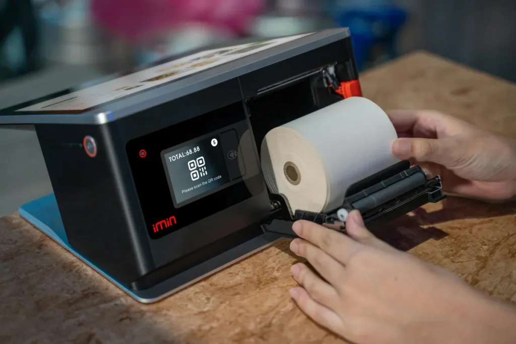 Tangan memasang gulungan kertas thermal ke dalam perangkat printer kasir touchscreen